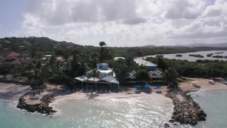A resort on the beach with ocean waves hitting the shore at midday