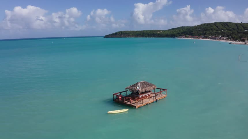 Aquatic hut in the middle of the ocean with the coast in the background
