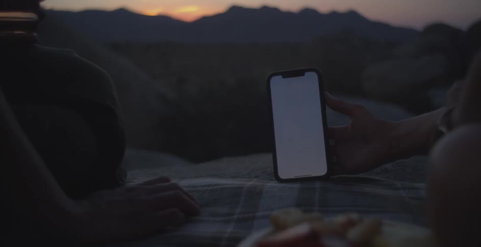 Person holding a smartphone on a mountain at dusk