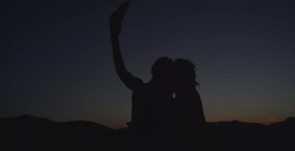 Silhouette of two young women taking a selfie outdoors with a mobile phone at night