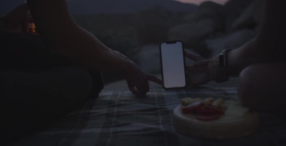 Two people interacting with a smartphone in the mountains