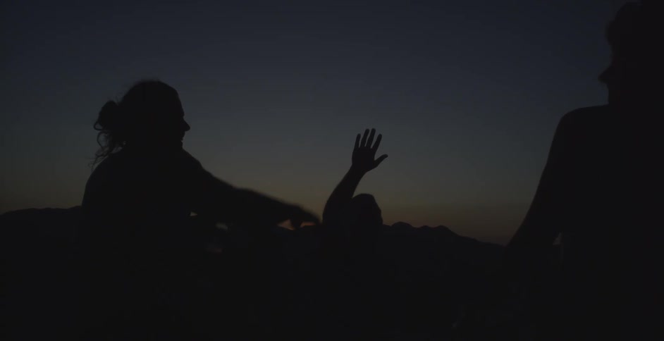 Friends silhouetted against the sky at night high five each other and jump for fun