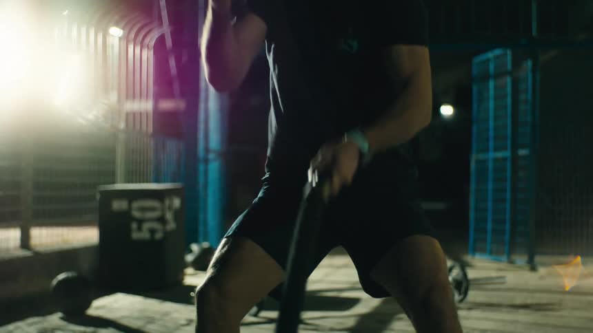 Person hitting ropes in a gym at night