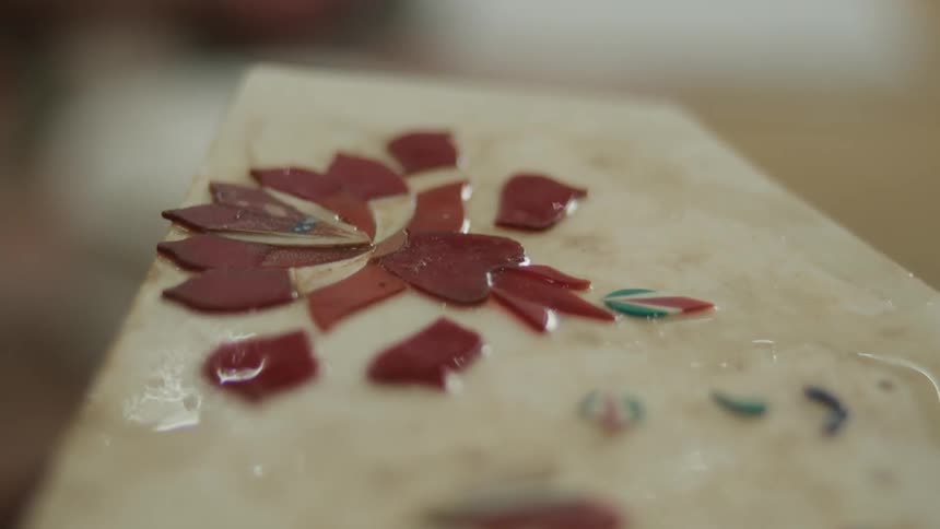 Artwork is being created using colorful chips and adhesive