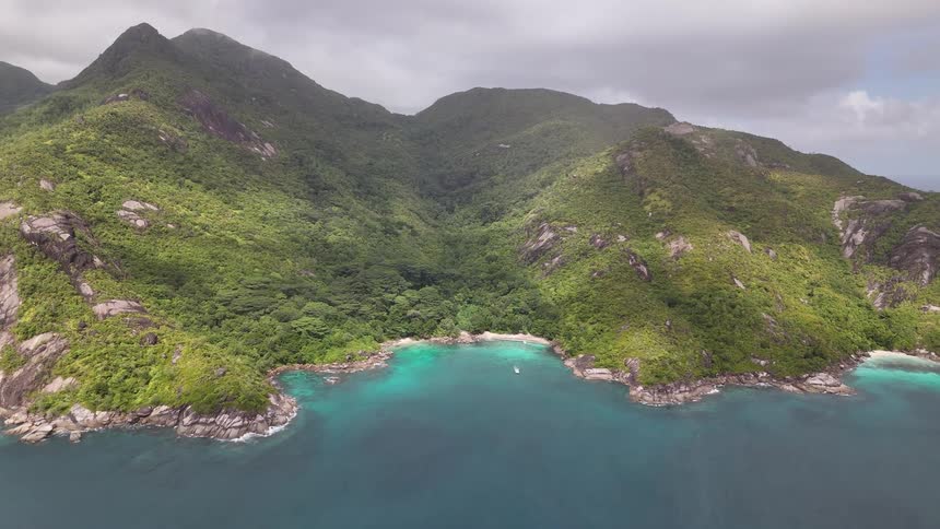 Aerial view of towering mountains by the sea on a cloudy day