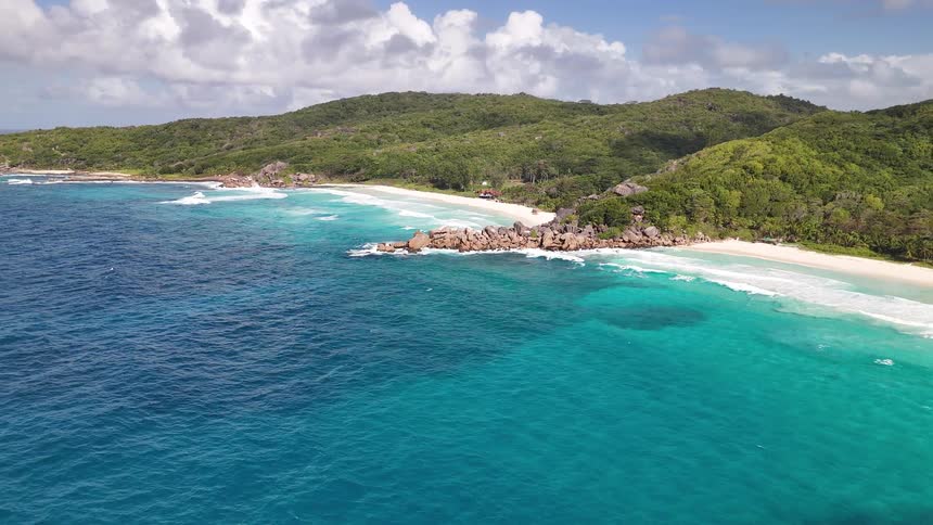Turquoise blue beach with forested mountains in the background