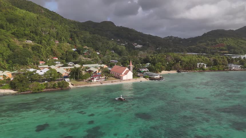 A coastal town surrounded by trees and vegetation features a church on the shoreline