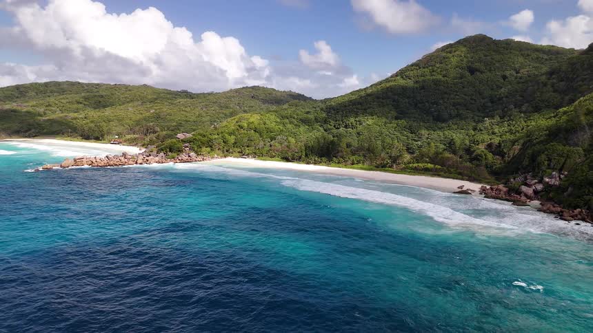 Landscape of a wooded coastline on the edge of a turquoise blue beach