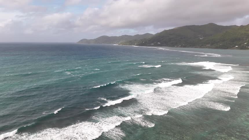 An ocean view from the shoreline with waves hitting the shore