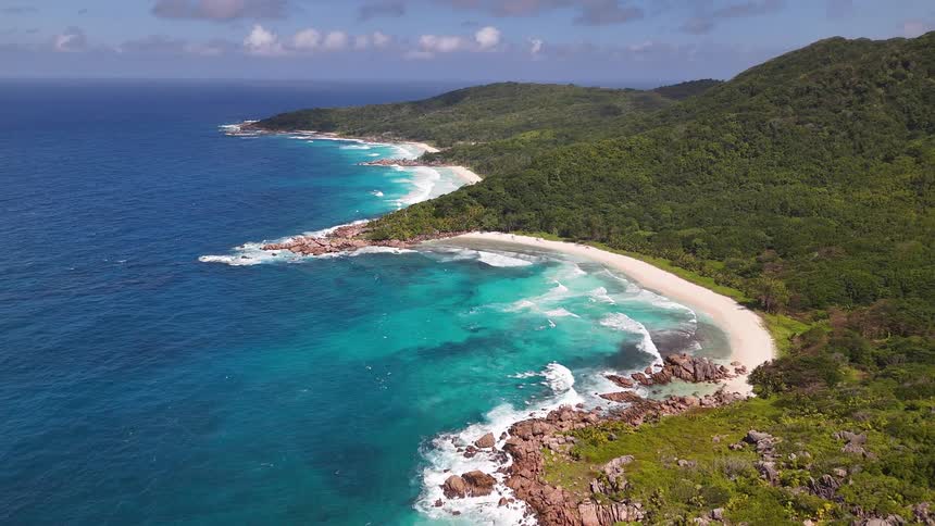 A mountainous island covered with vegetation is surrounded by the ocean
