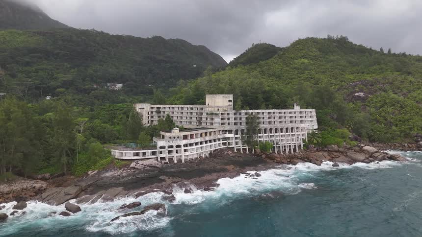 The abandoned mah beach hotel in seychelles is surrounded by green vegetation at midday