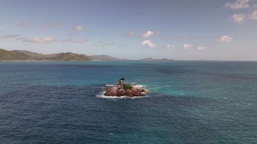 A small island is in the ocean before larger ones in the distance