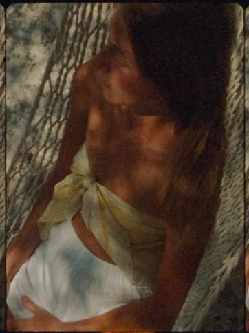 A woman relaxes on a hammock in dappled sunlight