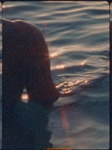 A persons hand floats just above the surface of calm bluish water midmotion