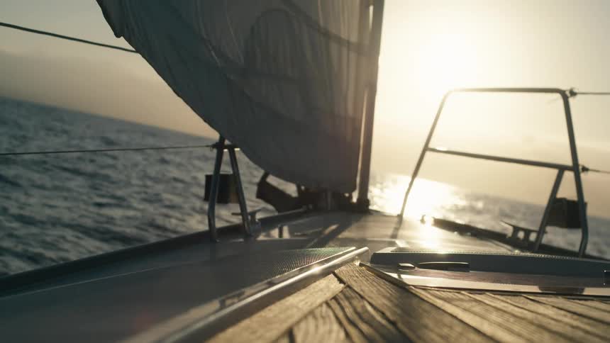 Boat moving across the ocean with the sun on the horizon
