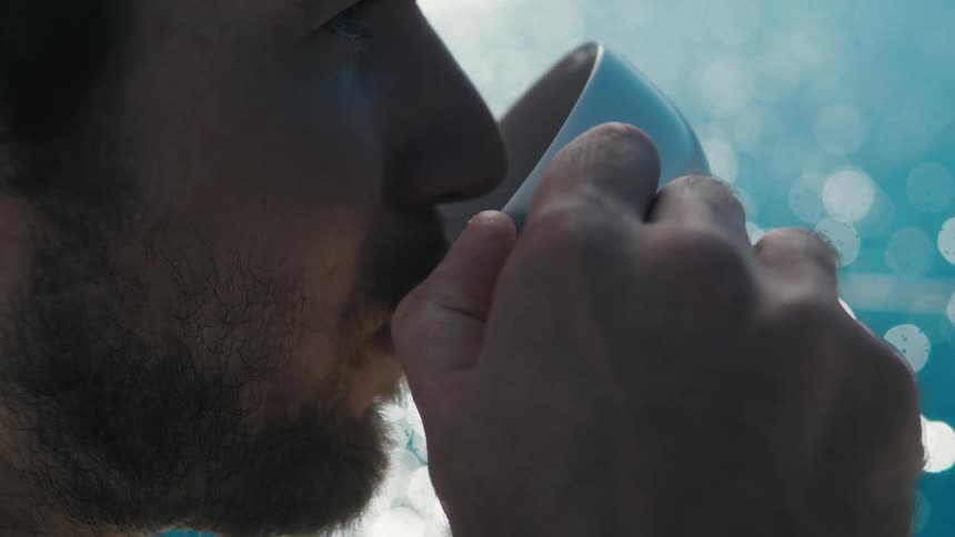 Man drinking from a cup by the sea