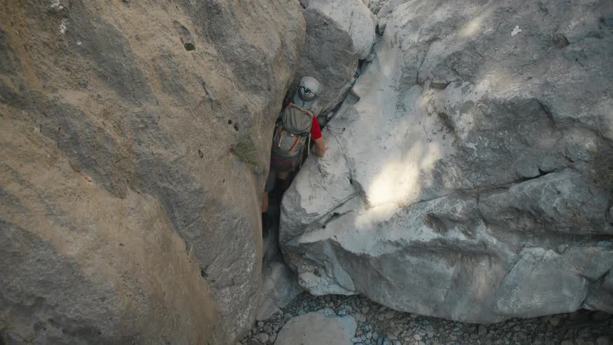 Man in hat climbing rocks in a natural environment