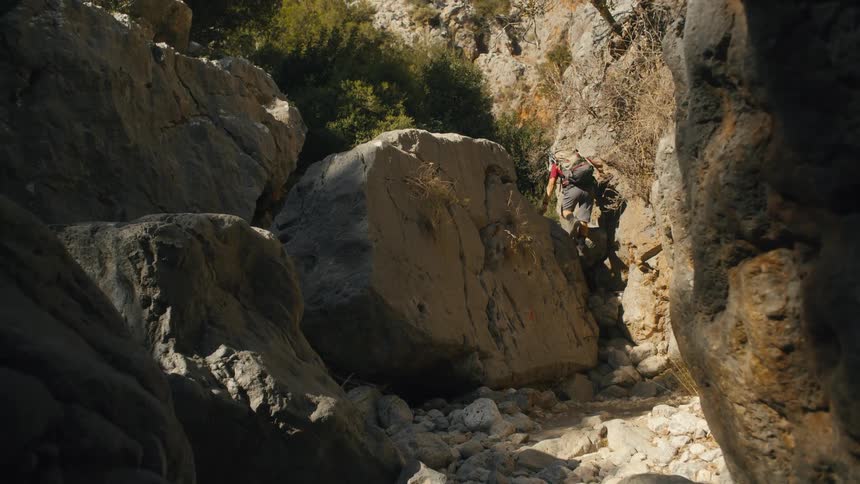 Man with hat and backpack hiking among rocks