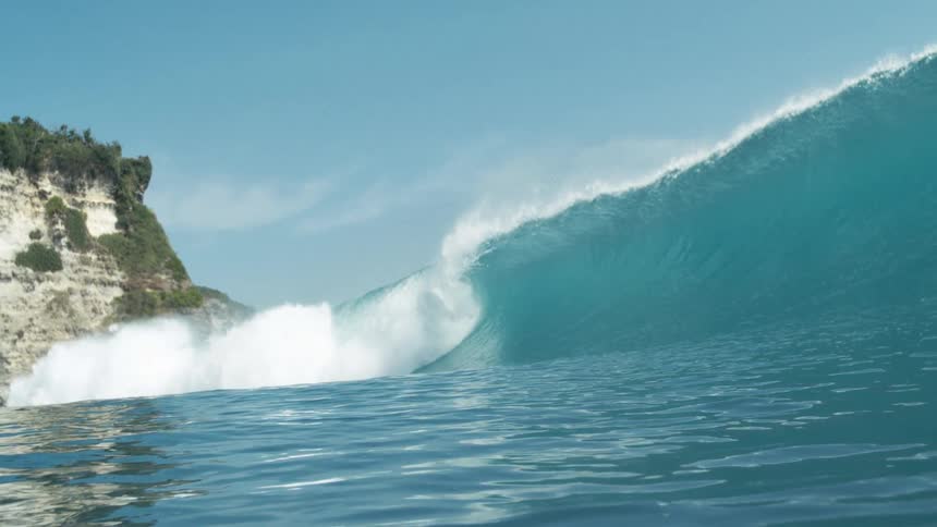 Crystal clear blue wave breaking tubularly in the ocean