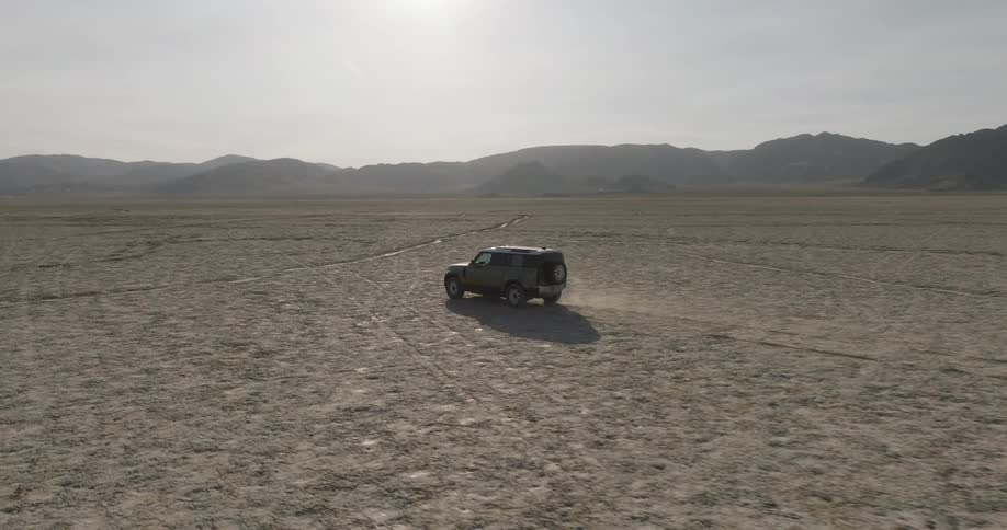 Vehicle traveling on a dry road with mountains on the horizon