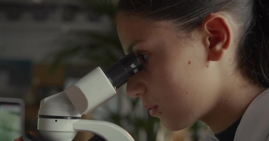 Woman approaching her face and eyes with a microscope