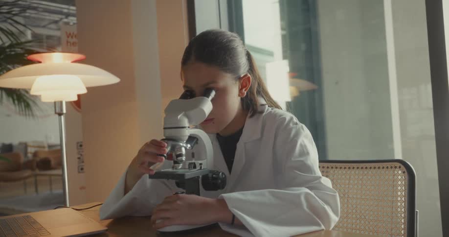 Woman in white coat interacting with a microscope on the table