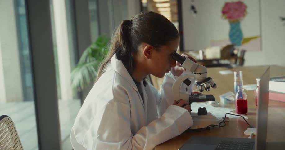 Young woman using a microscope on the table