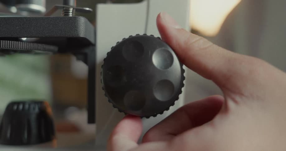 Hand turning a microscope stand knob