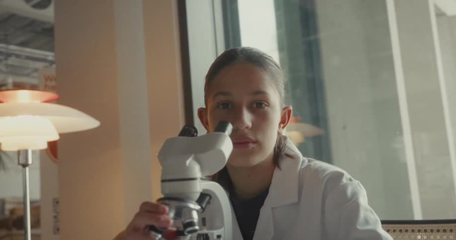 The scientist looks away from the microscope