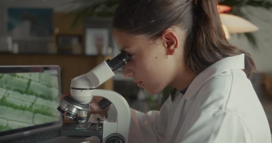 Concentrated woman using a microscope on the table