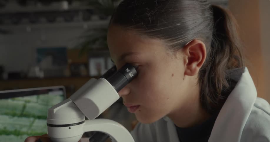 The girl is using a microscope to examine something
