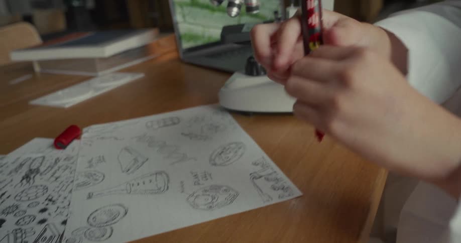 Young female scientist circles a diagram on a paper after viewing a microscope slide in a lab during daytime