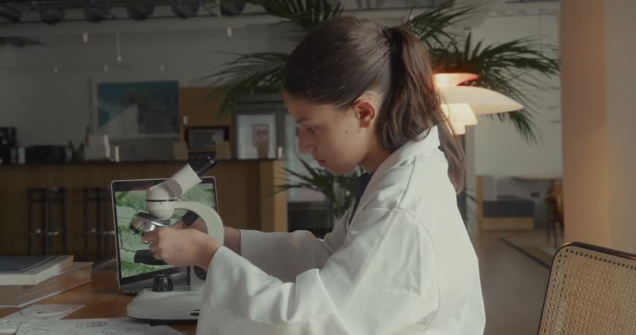 A girl puts a slide in the microscope