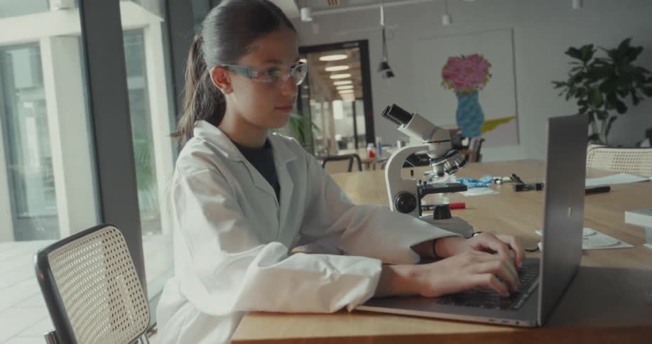 Young woman in white coat sitting typing on a laptop