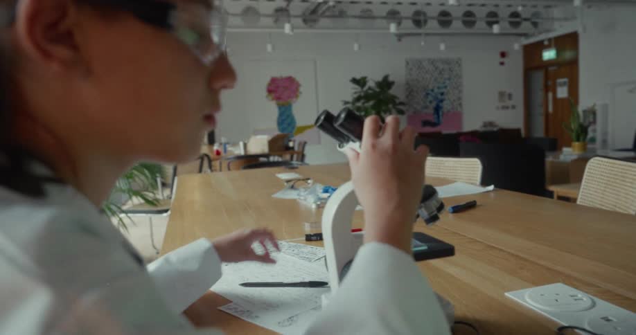 Teenager using a microscope and taking notes