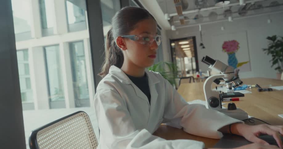 The teenager is typing on the laptop in the laboratory