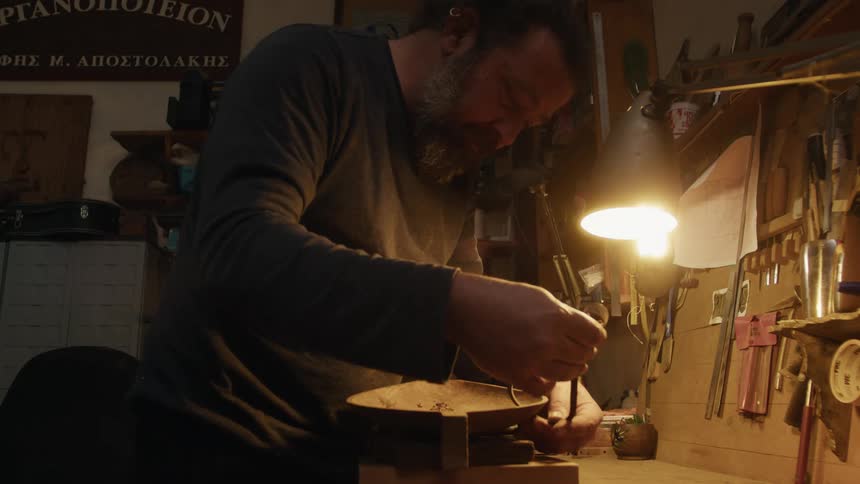 Man with a tool carefully carving a wooden container