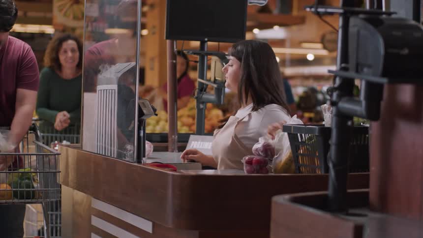 Cashier scans items as man unloads cart at checkout