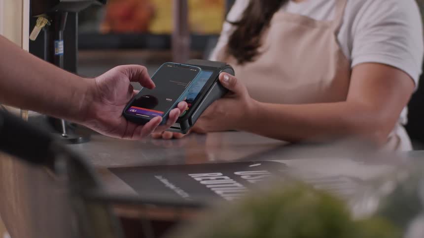 A customer makes a contactless payment with a smartphone at a caf counter