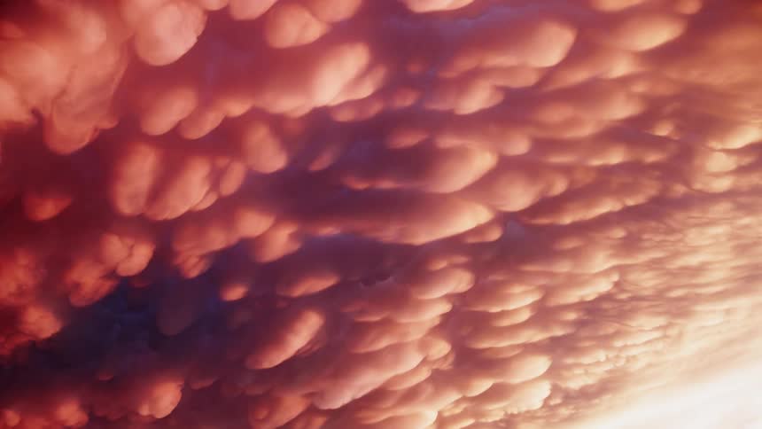 Mammatus cloud formations illuminated by warm tones create a dramatic wavy sky