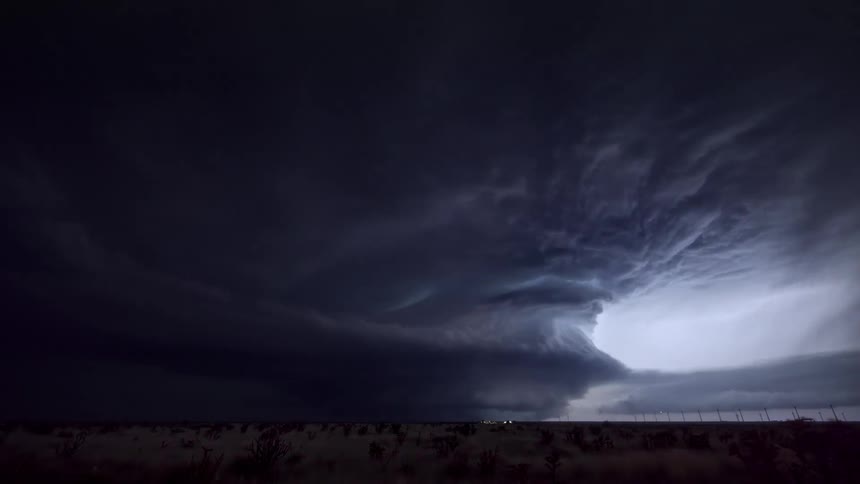 Rotating supercell flashing at night in desert area with sparse vegetation