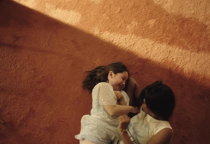 Two children lying down tickling each other playfully