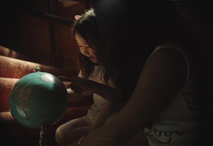 Two children playing with a globe on the stairs of a house