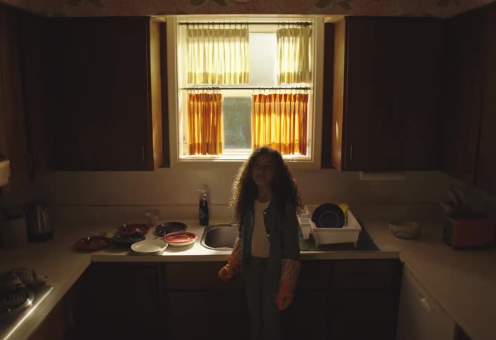 Curly haired girl with gloves next to the sink in the kitchen