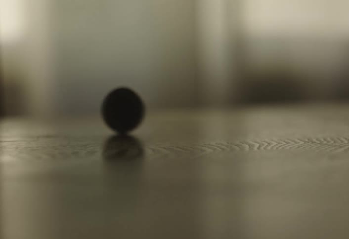A coin spins on a table as a hand then quickly snatches it up