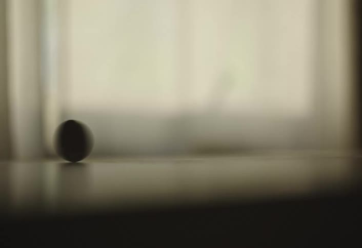 Close up of a coin spinning on a window sill indoors during daytime