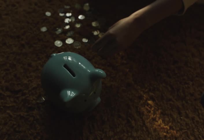 Hand putting coins into a piggy bank on a rug