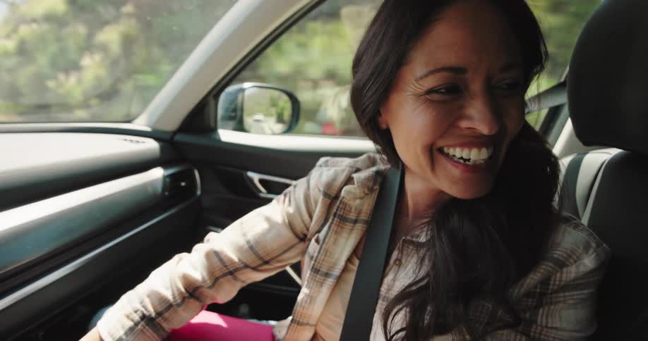 A woman laughs and looks back in the car