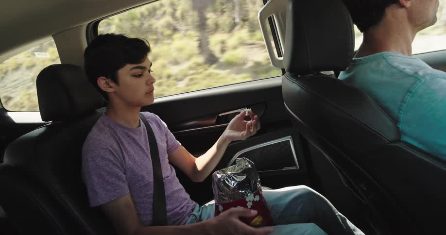 Boy eating snacks inside a moving car
