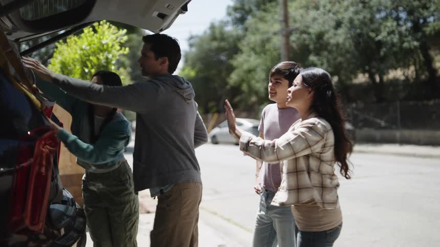 Family storing backpacks and suitcases in the trunk of the car
